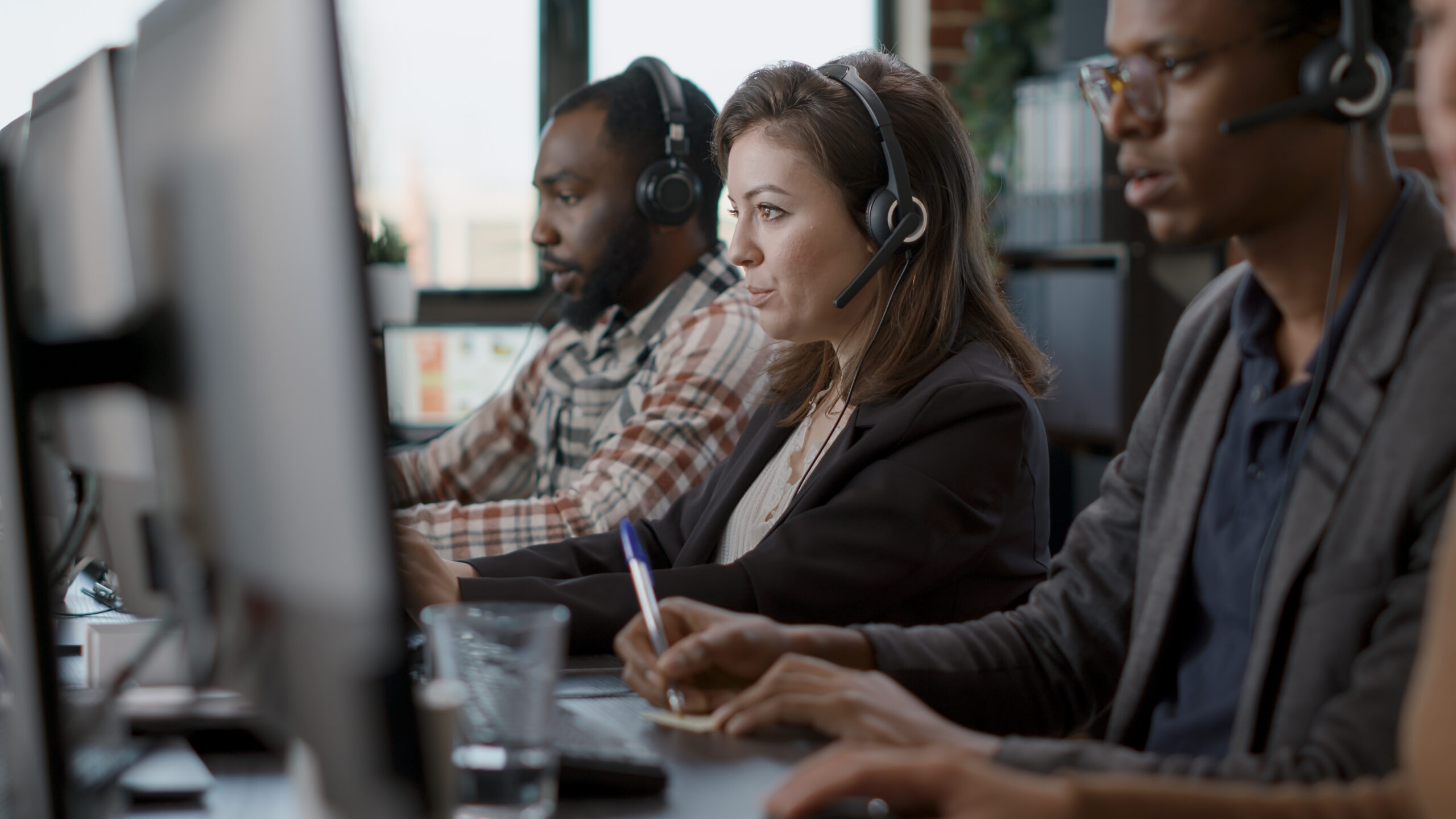 young woman using audio headset and computer at call center