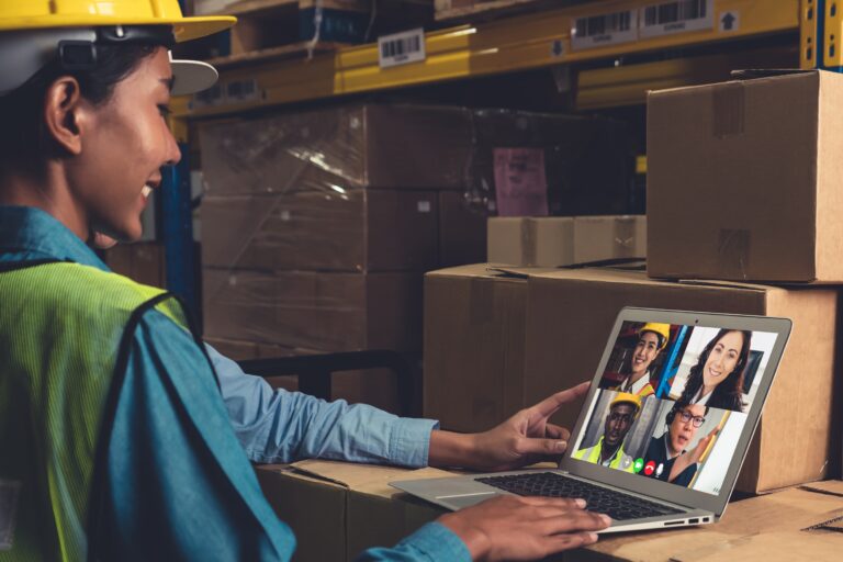 warehouse staff talking on video call at computer screen in stor